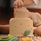 Child's hand playing with a natural wood toaster and pretend breakfast food items