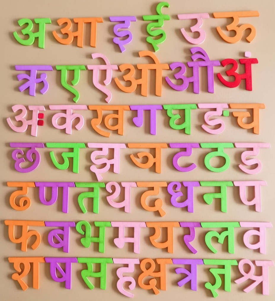 Wooden Hindi Varnamala learning board with all colorful alphabet pieces displayed.