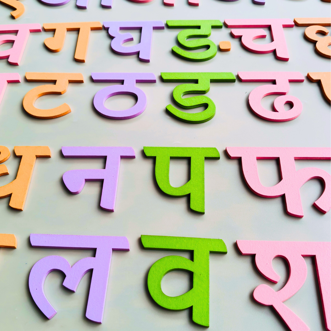 Overhead shot of the varnamala board with a few letters removed, highlighting the intricate cut-outs.